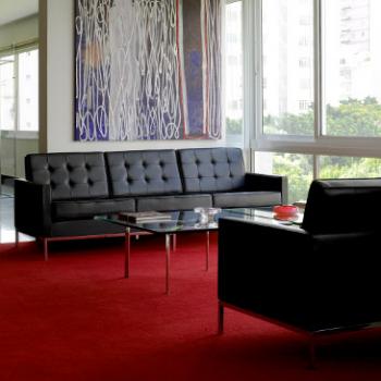 2 black Florence Knoll sofas on a red carpet with a glass coffee table