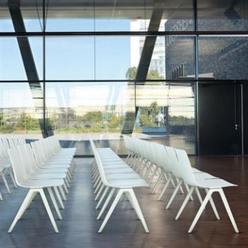 Rows of white A-Chairs by large glass window